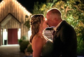 Newlyweds kissing in front of barn at night in the hill country