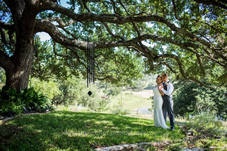 wedding couple under an Oak Tree in the lawn at Paniolo Ranch